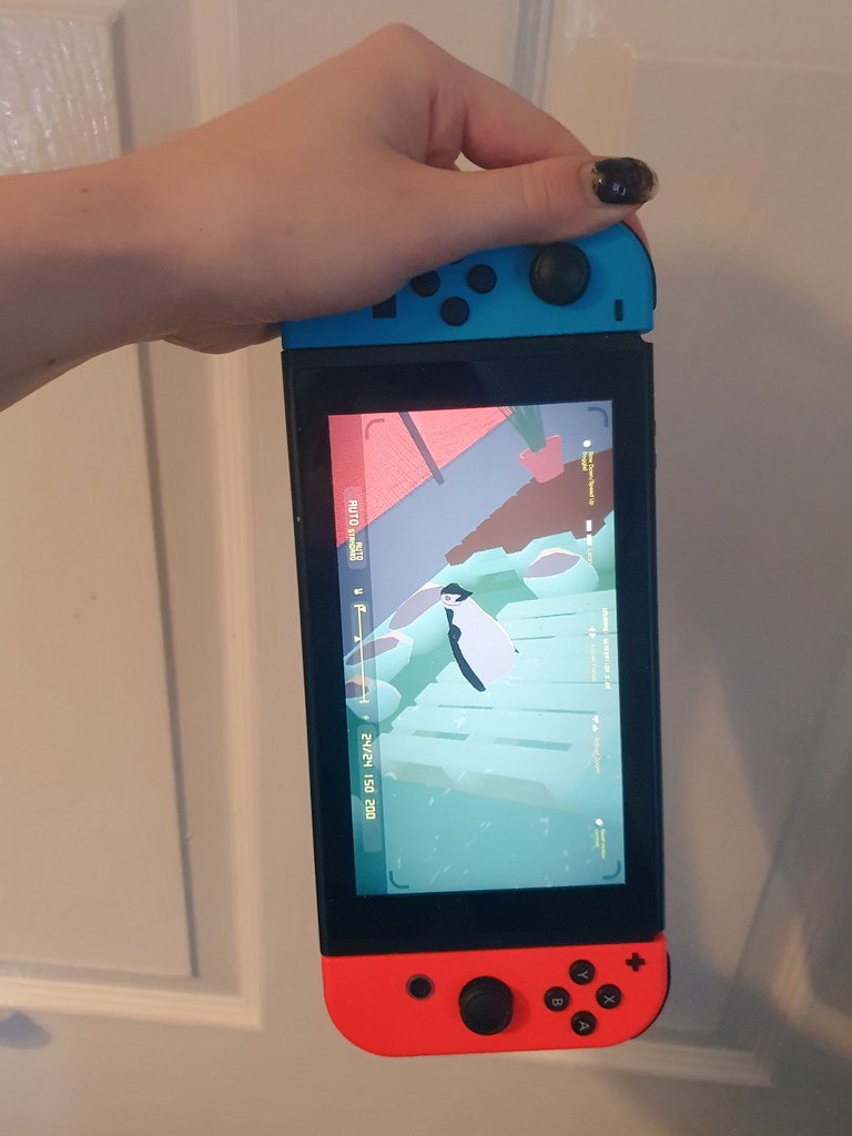A hold holding a Nintendo Switch, showing the game in progress.