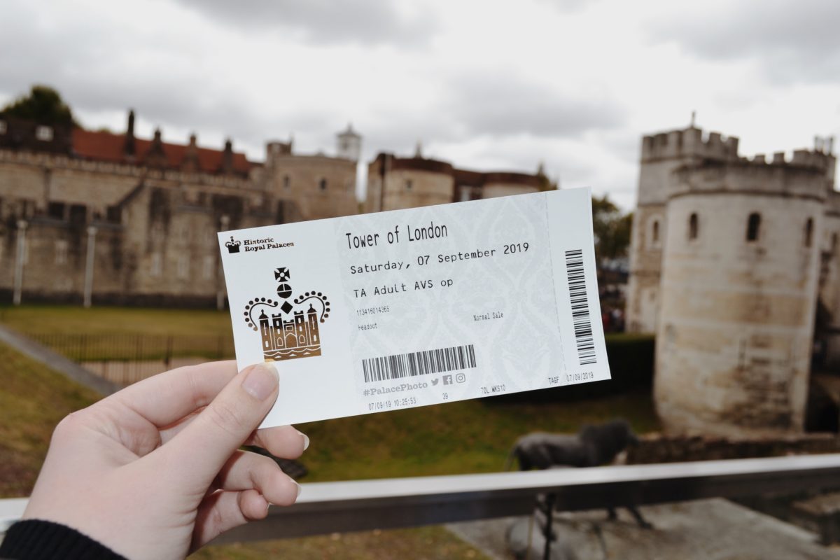 A picture of a ticket to the Tower of London held in front of the Tower of London